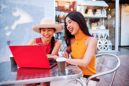 two asian girls using a credit card to pay or purchase using a notebookの写真素材