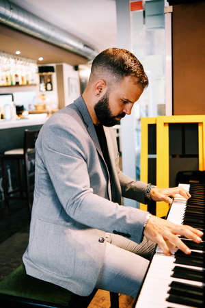 adult man wearing a grey suit playing the piano at the barの写真素材