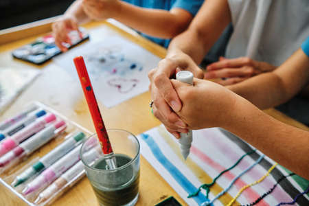 mother hands helps his young son to draw and paintの写真素材