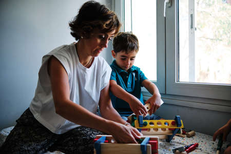 a mother playing with toys with her children on the bed at homeの写真素材
