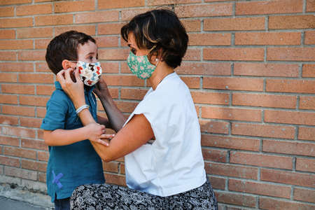 a mother puts a mask to his son in the streetの写真素材