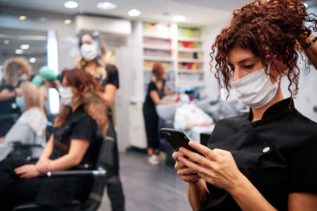 woman in hairdressing salon checking her mobile - new normalの写真素材