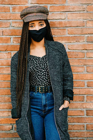 portrait of black woman with braids using a protective mask during coronavirus pandemicの写真素材