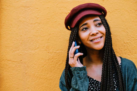 black woman with braids making phone call with smartphone