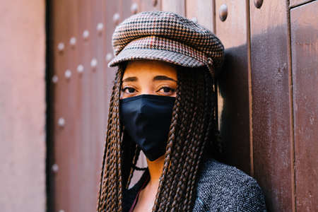 portrait of black woman with braids using a protective mask during coronavirus pandemic