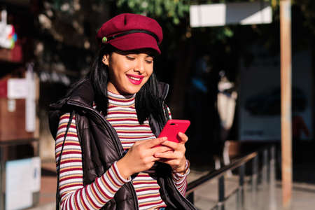 young middle east girl using a red smartphone outdoors