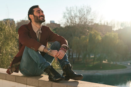 Man smiling while sitting outdoors at park.の写真素材