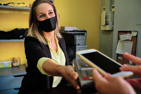 woman with protective mask using credit card to pay contactless - new normalの写真素材