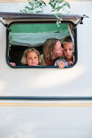 a mother and her children looks trhough the window of her caravanの写真素材