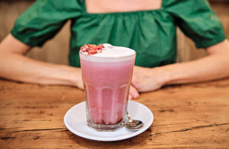 a pink smoothie with unrecognizable woman behindの写真素材