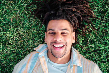 close up of funny latin man with curly hair lying on the grass