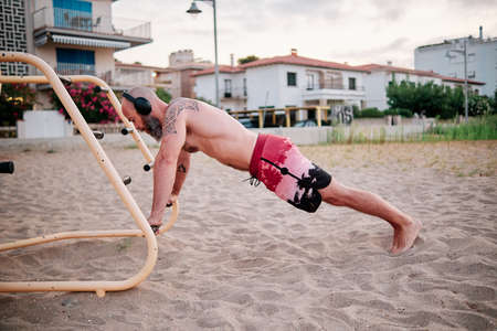 Strong athlete man doing exercises in calisthenics park on the beach.の写真素材