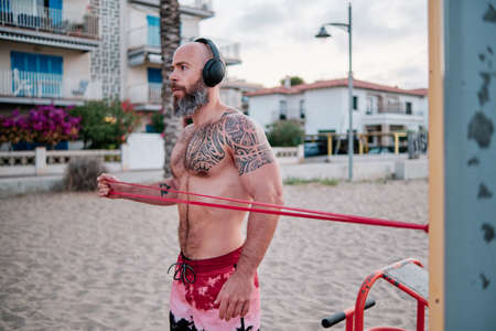Fitness man doing calisthenics workout with a resistance rubber band.の写真素材