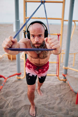 Fitness man doing calisthenics workout with a resistance rubber band.の写真素材