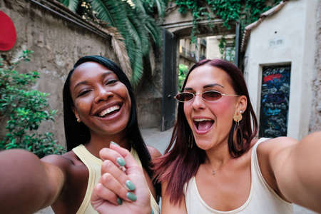 Two female friends having fun while taking selfies together outdoors.の写真素材