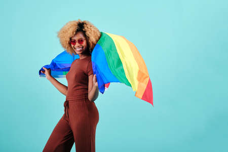 Cheerful young afro woman waving a pride flag over an isolated background.の写真素材