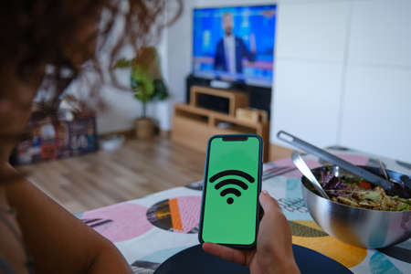 Woman using an app on her mobile phone to control the appliances in her smart home. IoT Internet of Things concept.の写真素材