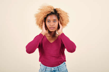Woman with afro hairstyle looking seriously at the camera on an isolated background.