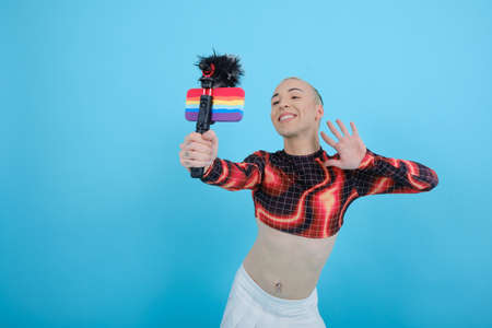 Smiling and happy non-binary social influencer person vlogging online with a mobile phone.の写真素材