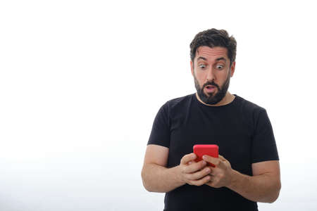 Man looking surprised at his mobile phone while standing on an isolated background.