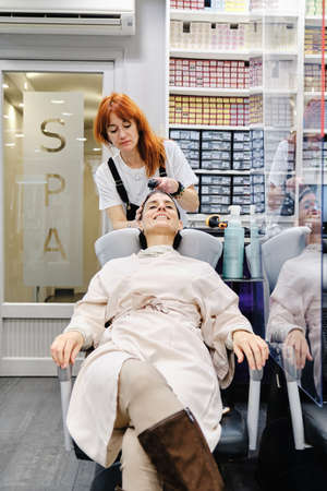 Hairdresser washing the hair of a female client in the beauty salon.