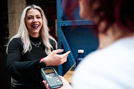 Woman making contactless payment with a smart watch at a coffee shop.の写真素材