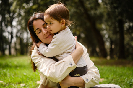 Mother hugging her little daughter while they enjoy a day together outdoors in nature.の写真素材