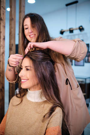 Stylist making a hairstyle to a female client in the hair salon.の写真素材