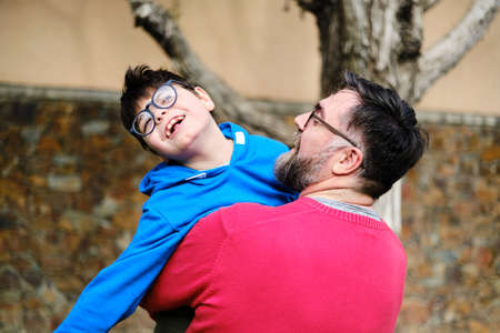 Loving father holding and playing with his disabled son while enjoying time together outdoors.の写真素材