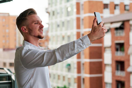 Young executive businessman using a mobile phone while standing on a balcony.の写真素材