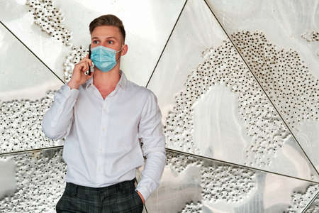 Executive man using a face mask while talking on the mobile phone.の写真素材