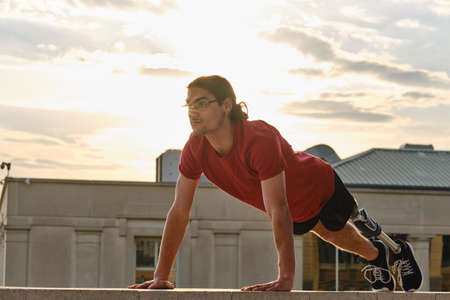 Sporty man with a disability doing push-ups while exercising outdoors.