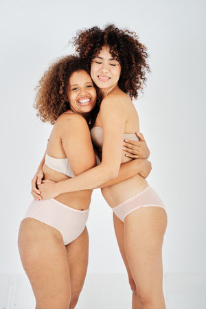 Glad women with curly hair embracing each otherの写真素材