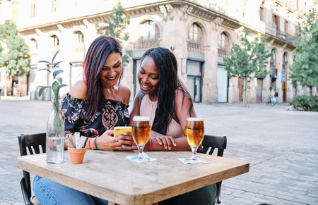 Friends drinking a beer and using the mobile outdoors