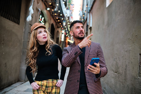 Couple using a mobile while pointing to a direction outdoorsの写真素材