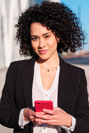 Businesswoman using a mobile in the city streetの写真素材