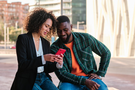 Multiethnic couple using a mobile outdoors in the city