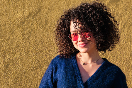 Cute smiley woman with curly hair and heart shape sunglasses