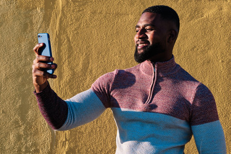 African man taking a selfie outdoors in a sunny dayの写真素材