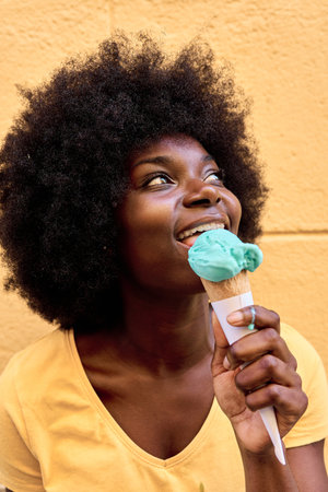 Distracted african woman eating an ice creamの写真素材