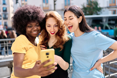Curious and happy women sharing a mobile in the streetの写真素材