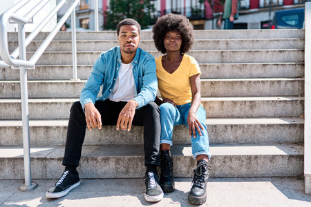 Stylish african friends sitting on stairs in the streetの写真素材