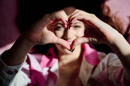 Close up view of a woman making a heart shape with her hands.の写真素材
