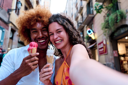 multiethnic couple enjoying summer in the city and taking selfie while eating ice creamの写真素材