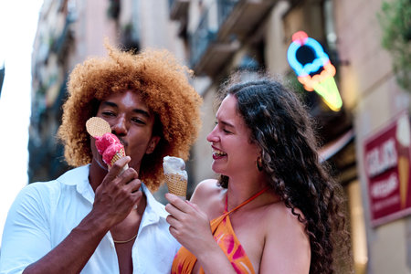 black man with afro hair and his girlfriend eating ice cream in a summer day in Barcelonaの写真素材