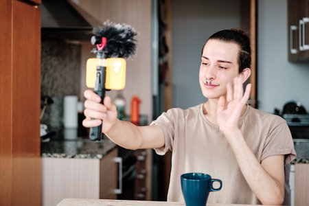 Gay man waving during a video call from home