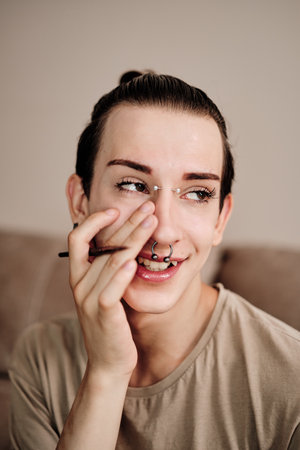 Happy young gay man applying make up at home