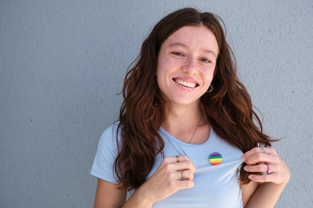 Young and smiling woman showing a Rainbow Badge