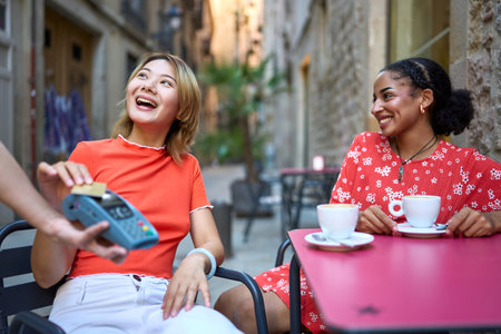 Chinese girl paying with card next to her girlfriendの写真素材