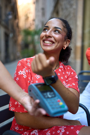 Woman using smart watch to pay in an outdoors cafeteria